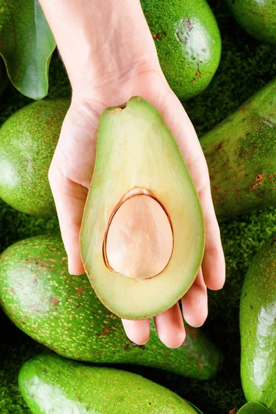 Ruce drží polovinu čerstvé zralé avokádo. Zdravá eco jídlo — Stock fotografie