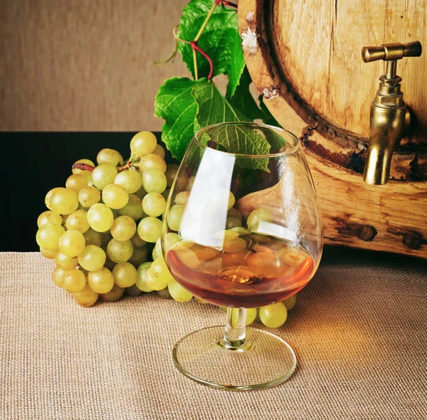 Copo de conhaque e cacho de uva madura na mesa — Fotografia de Stock