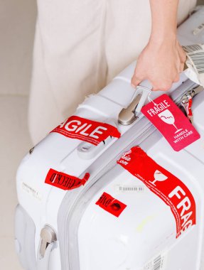 Bagaj etiketi (Fragile) beyaz çantayla havaalanında tutan adam