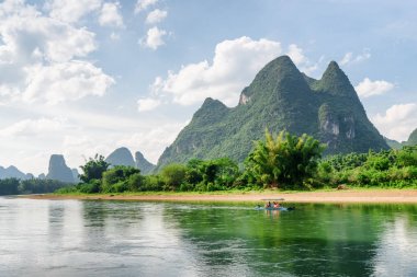 Yeşil ağaçların arasında Li Nehri üzerinde turist motorlu Sal