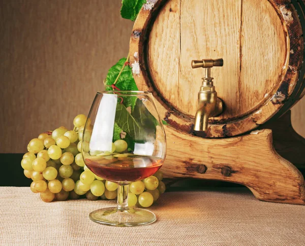 Copo de conhaque, cacho de uva madura e barril de conhaque — Fotografia de Stock