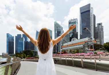 Young woman with raised arms on skyscrapers background