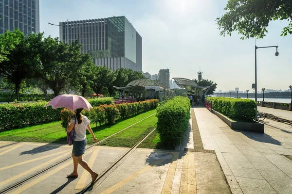 Turista donna con ombrello che attraversa pista erbosa, Guangzhou — Foto Stock