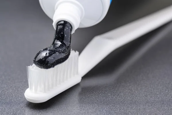 Черный древесный уголь отбеливающий зубную пасту на белой зубной щетке — стоковое фото