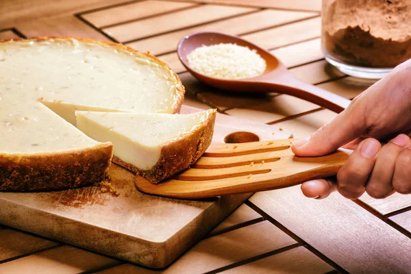 Hand taking piece of delicious freshly baked cheesecake — Stock Photo, Image