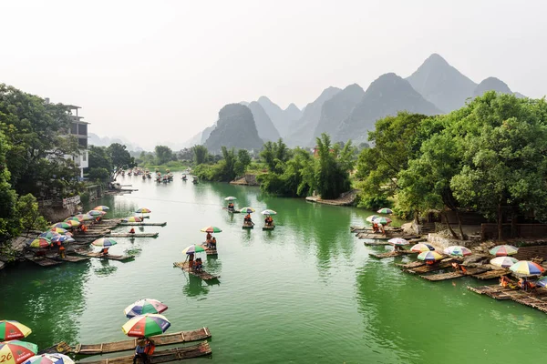 Turisti che viaggiano con piccole zattere di bambù lungo il fiume Yulong — Foto Stock