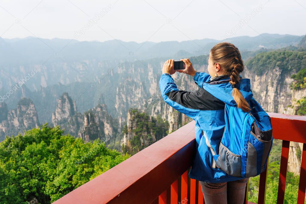 Female tourist taking photo of Zhangjiajie mountains. China