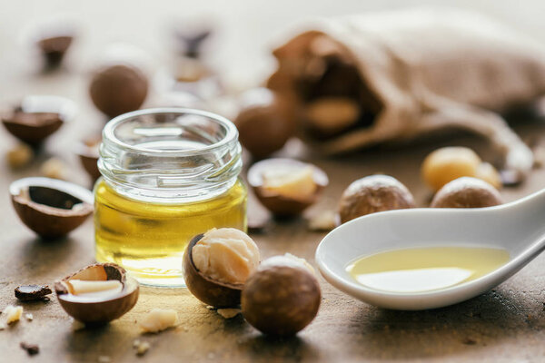 Natural macadamia oil and Macadamia nuts on wooden board