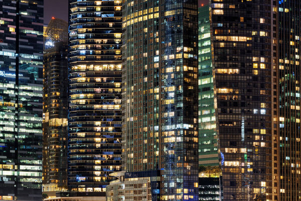 Scenic glowing windows of skyscrapers at evening. View of modern office high-rise buildings in Singapore. Beautiful night cityscape.