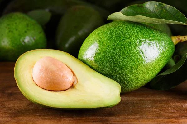 Rijpe groene avocado op houten tafel. Vers geoogste fruit — Stockfoto