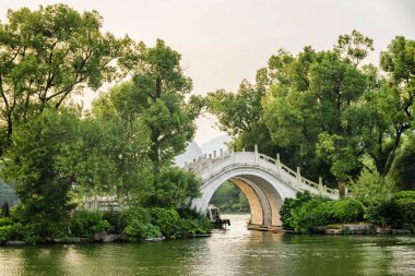 Doğal mermer köprü göl günbatımı, Guilin, ağaçlar arasında '