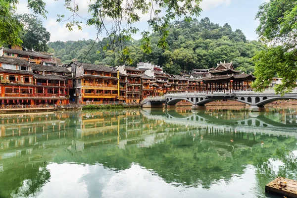 Traditional Chinese buildings and bridge reflected in water