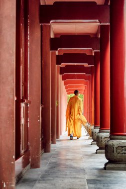 Budist keşiş, tapınağa giden kırmızı ahşap koridorda yürüyor.