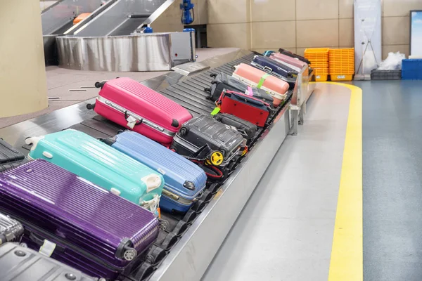 Heldere kleurrijke koffers op de bagageband op de luchthaven — Stockfoto