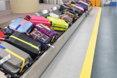 Parlak yeşil, pembe ve mavi valizler bagaj taşıyıcı bandında