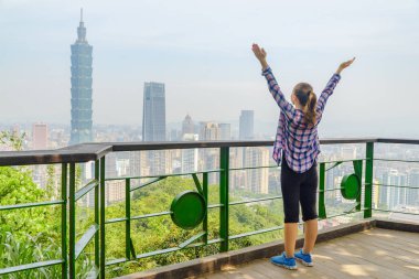Kollarını kaldırıp Taipei manzarasının tadını çıkaran kadın turist.