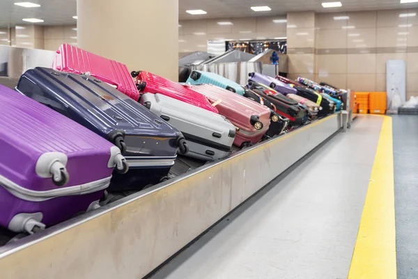 Violet and pink suitcases on luggage conveyor belt in airport — Stock Photo, Image