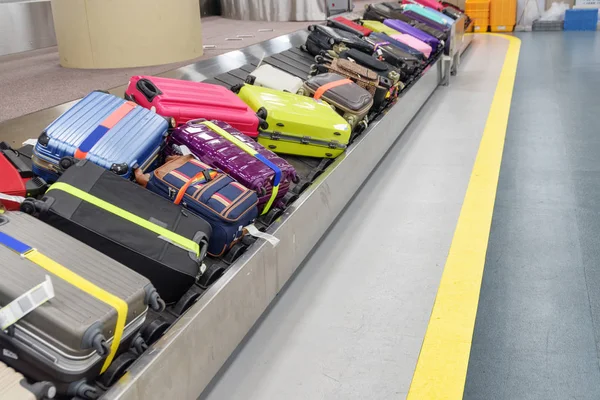 Parlak yeşil, pembe ve mavi valizler bagaj taşıyıcı bandında — Stok fotoğraf