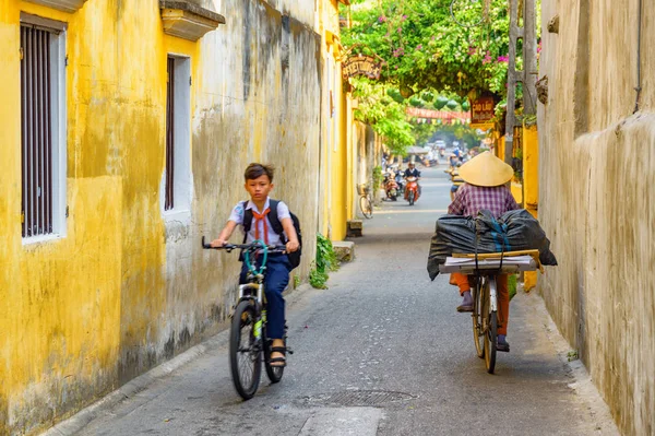 Skolpojke cykling längs smal gata Hoi An, Vietnam — Stockfoto