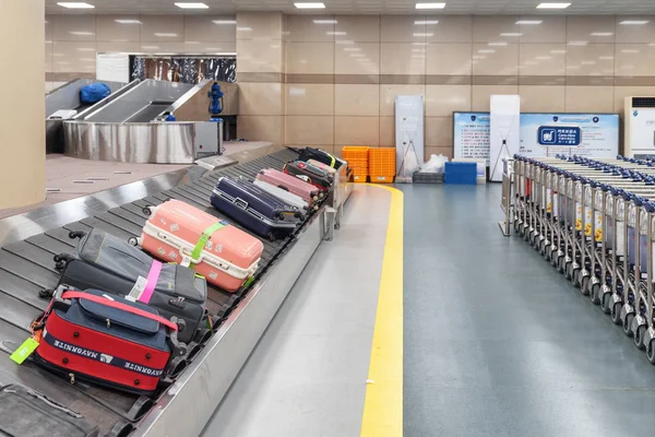 Koffers op de bagageband en rijen trolleys — Stockfoto