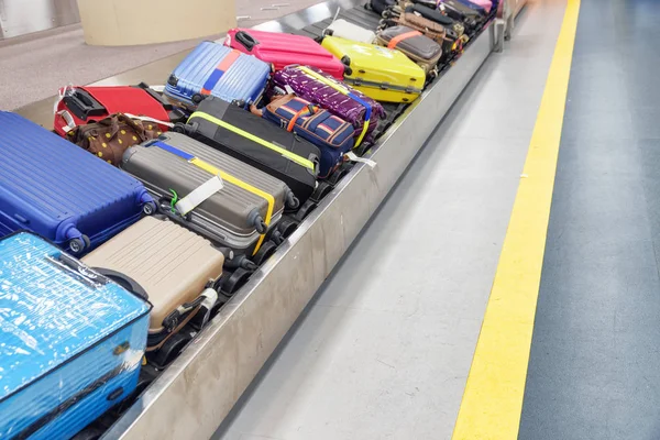 Kleurrijke koffers en tassen op de bagageband op de luchthaven — Stockfoto