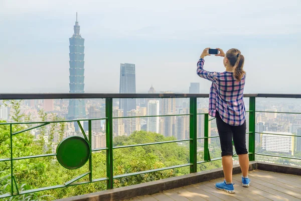 Dağın tepesinden Taipei manzarasının tadını çıkaran kadın turist. Muhteşem Taipei silueti, Tayvan. Harika bir şehir manzarası. Gökdelenler ve şehir merkezindeki diğer modern binalar.