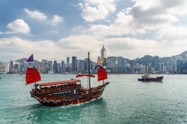 Hong Kong - 20 Ekim 2017: Victoria Limanı 'nda kırmızı yelkenli geleneksel Çin ahşap yelkenli gemisinin muhteşem manzarası. Güneşli bir günde Hong Kong Adası ufuk çizgisi. İnanılmaz bir şehir manzarası.