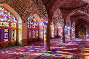 Şiraz, İran - 31 Ekim 2018: Nasir al-Mulk Camii 'ndeki (Pembe Cami) sabah namazının güzel manzarası. Güneş ışığı, sütunlardaki, duvarlardaki ve yerdeki vitray pencerelerden yansıyor..