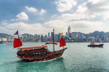 Hong Kong - 20 Ekim 2017: Victoria Limanı 'nda kırmızı yelkenli geleneksel Çin ahşap yelkenli gemisinin güzel manzarası. Güneşli bir günde Hong Kong Adası ufuk çizgisi. İnanılmaz bir şehir manzarası