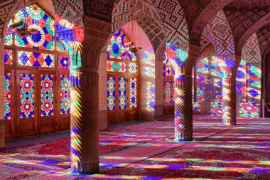 Nasir al-Mulk Camii 'ndeki (Pembe Cami) sabah namazının manzarası. Güneş ışığı, sütunlardaki, duvarlardaki ve yerdeki vitray pencerelerden yansıyor..