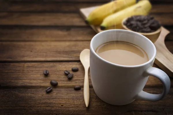 Cup of coffee with coffee beans and banana on wood table — Stock Photo, Image