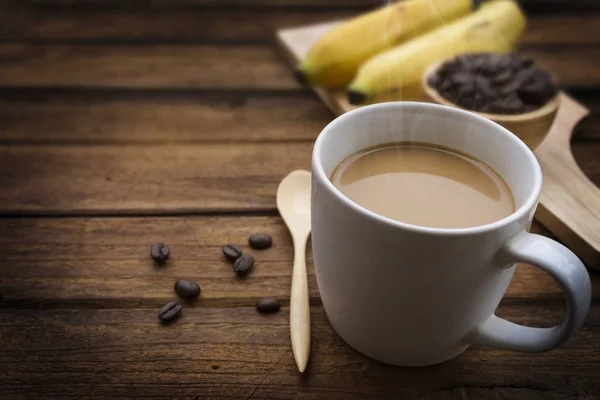 Kopje koffie met koffiebonen en banaan op houten tafel Stockafbeelding