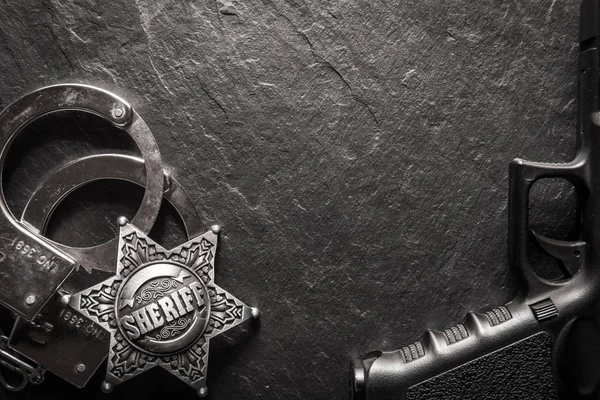 Sheriff star and handcuffs on black slate table — Stock Photo, Image