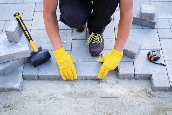 The master in yellow gloves lays paving stones — Stock Photo, Image