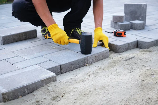 The master in yellow gloves lays paving stones — Stock Image The master in yellow gloves lays paving stones Royalty Free Stock Photos