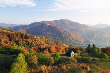 Ahşap evi olan resimli sonbahar çayırı