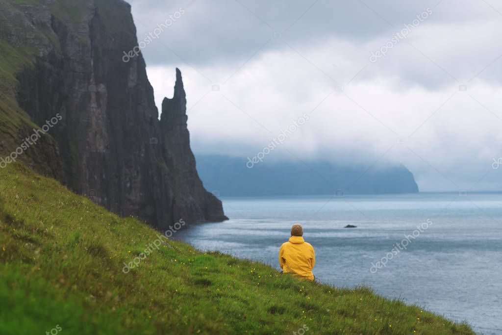 Tourist with backpack in yellow jacket looks at Witches Finger cliffs