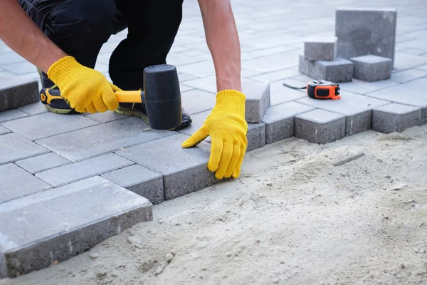 De meester in gele handschoenen legt straatstenen — Stockfoto