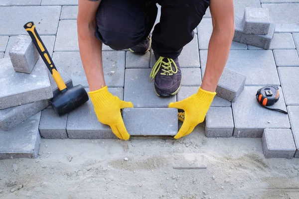 Le maître en gants jaunes pose des pavés — Photo