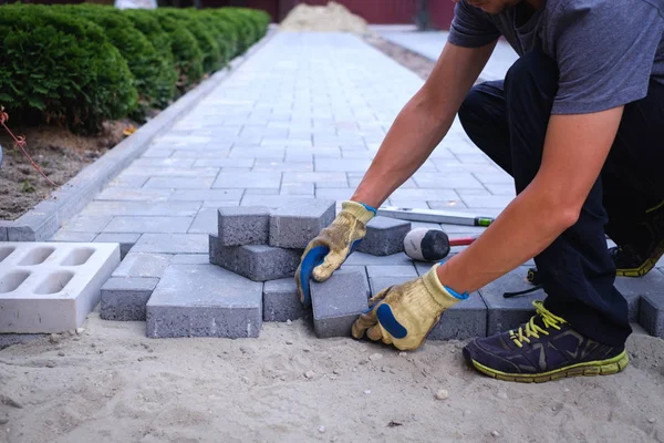 The master in yellow gloves lays paving stones — Stock Image The master in yellow gloves lays paving stones Stock Image