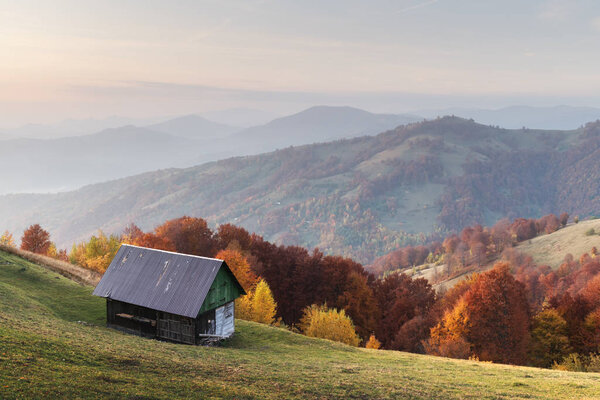 Picturesque autumn meadow with wooden house