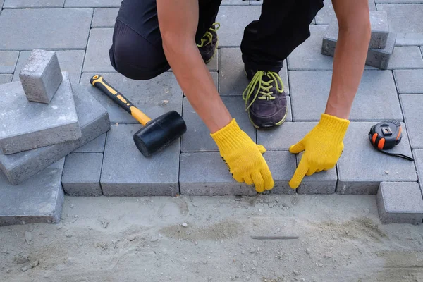 The master in yellow gloves lays paving stones — Stock Photo, Image