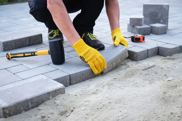 The master in yellow gloves lays paving stones — Stock Photo, Image