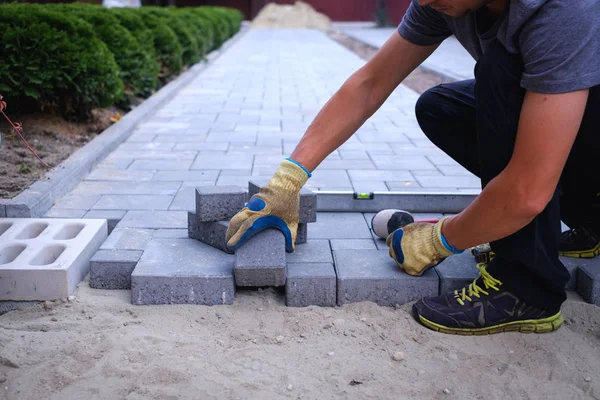 The master in yellow gloves lays paving stones — Stock Photo, Image