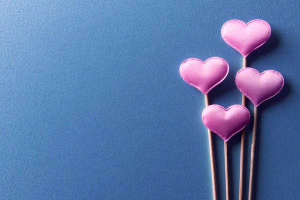 Różowe serca na drewnianych kijach na niebieskim tle zbliżenie — Zdjęcie stockowe