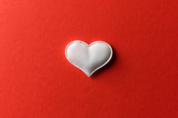 Corazón textil blanco sobre fondo rojo . — Foto de Stock