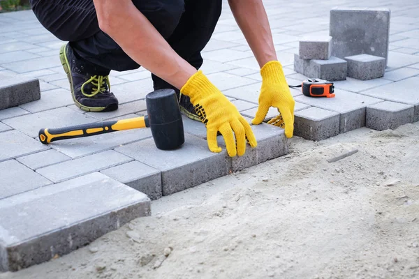 The master in yellow gloves lays paving stones — Stock Photo, Image