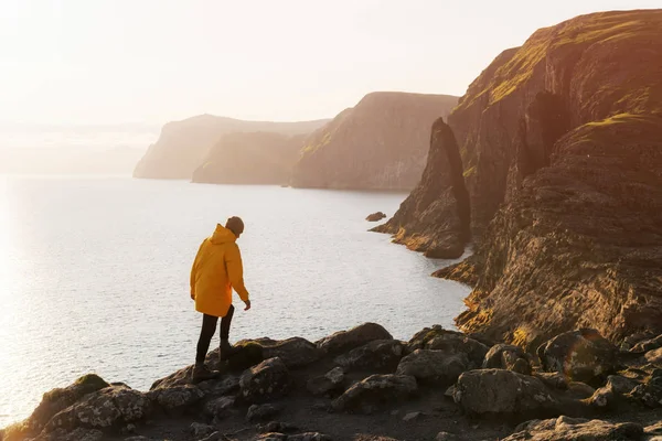 Турист в желтой куртке смотрит на скалы возле озера Сорвагсватн — стоковое фото