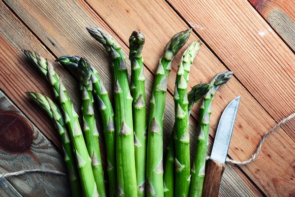 Groene asperges ontspruiten op houten plank — Stockfoto