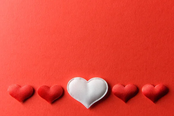 Red and white textile hearts on red paper — Stock Photo, Image